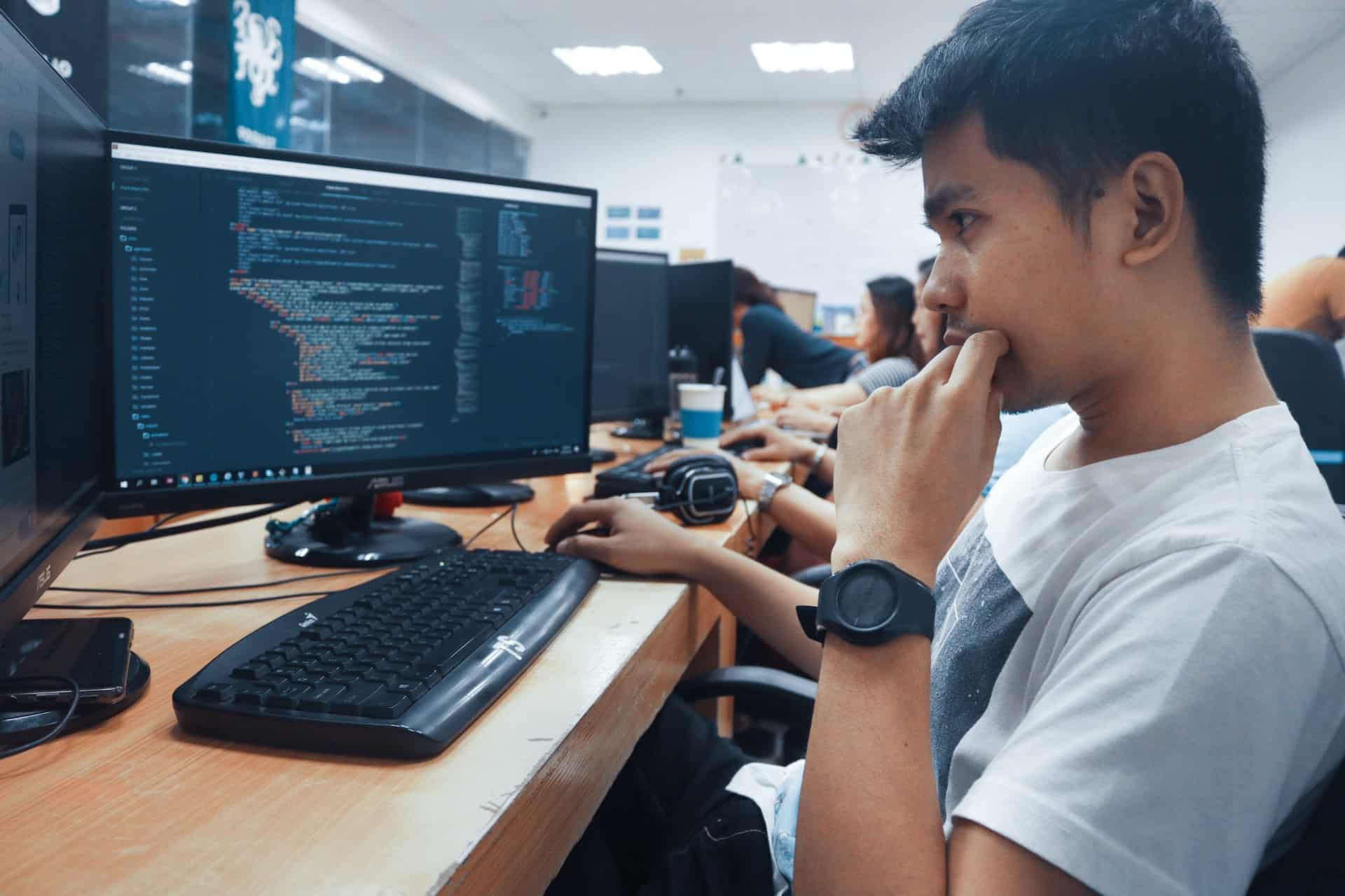 A imagem mostra um homem à frente do computador atuando como desenvolvedor front-end react