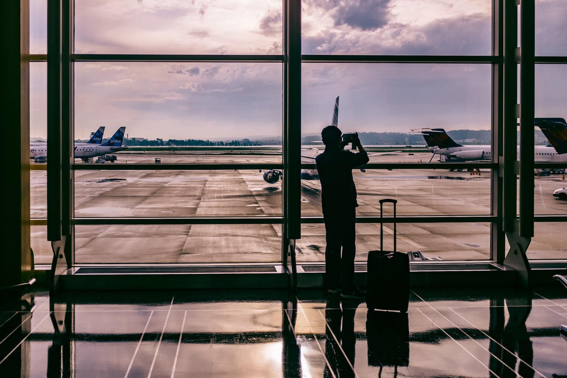 a imagem mostra um homem tirando foto da paisagem de um aeroporto, marcando o inicio de sua carreira internacional