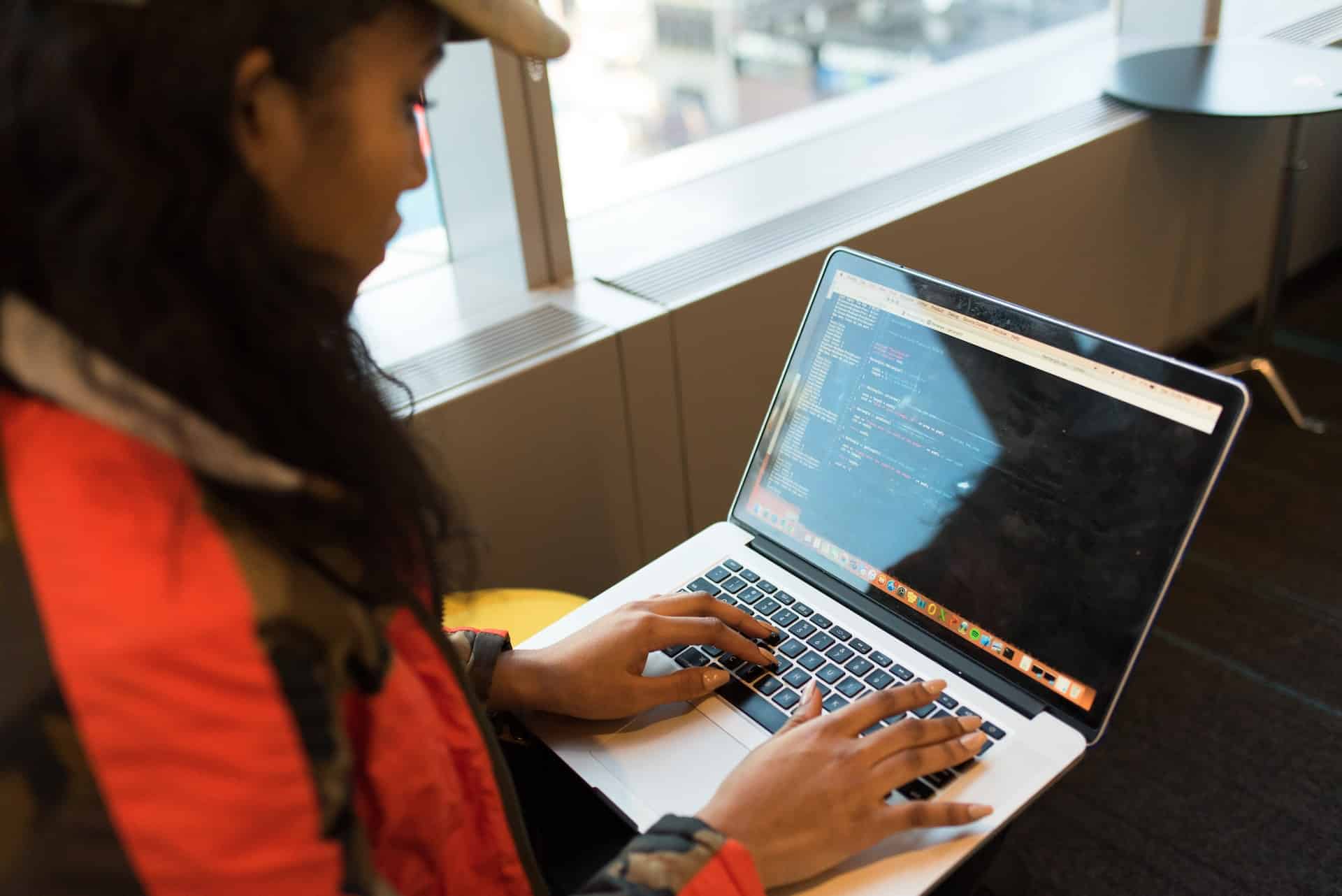 A imagem mostra uma mulher negra, com o computador sobre seu colo, atuando como uma desenvolvedora sênior